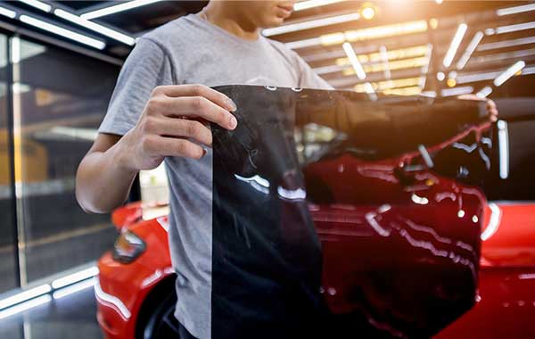 Technician holding dark window tint film during auto window tinting service in Kearny, New Jersey